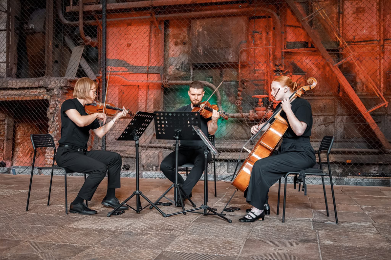 Na zdjęciu widać trójkę osób grających na instrumentach smyczkowych.