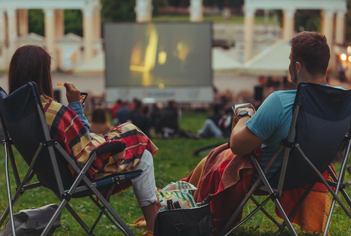 Para siedzi na leżakach i ogląda film kin plenerowego