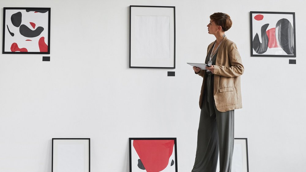 kobieta ogląda dzieła sztuki powieszone na ścianie i stojące na podłodze