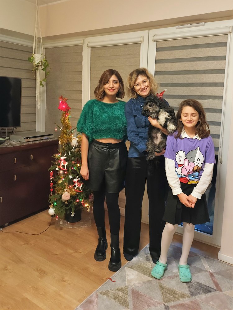 Uczestnicy akcji UŁ Gość na Gwiazdkę, trzy uśmiechające się kobiety i pies w czapce Mikołaja