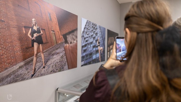 Osoba na przeciwko zdjęcia na ścianie galerii robi zdjęcie telefonem