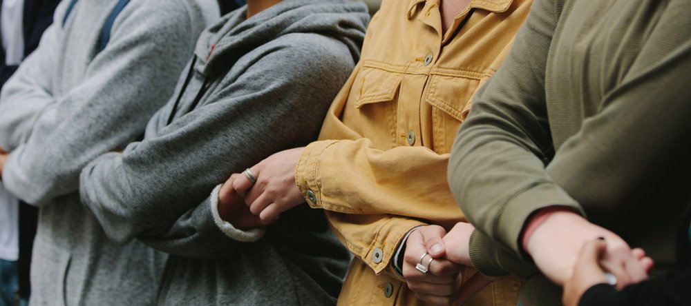 Osoby stojące obok siebie w rzędzie i trzymające się za ręce