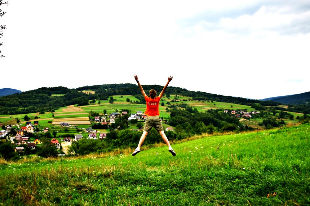 student w koszulce zespołu na zielonej polanie, podskakuje