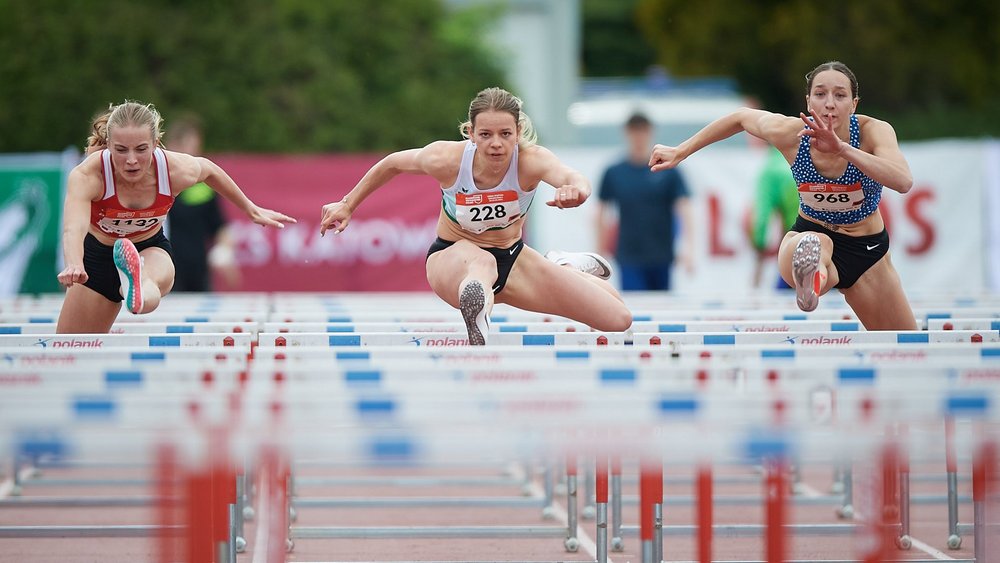 Sportowcy skaczący przez płotki