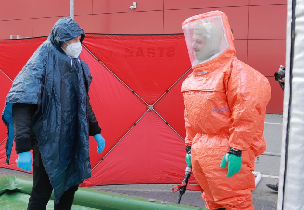 dwie osoby w strojach zabezpieczających ciało przed skażeniami 