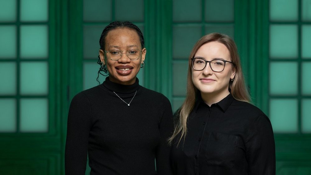 Zdjęcie Julity Maciejewskiej i Rumbidzai Hodzong. Dwie dziewczyny stoją obok siebie, są ubrane na czarno.