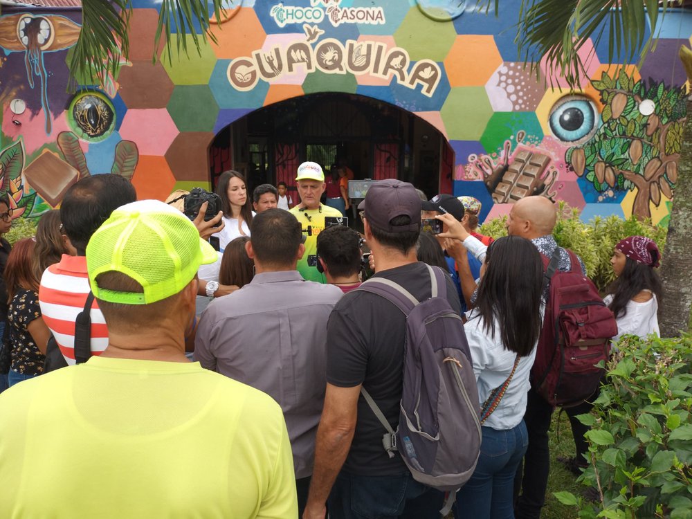 Grupa ludzi przed kolorowym wejściem do warsztatu czekolady