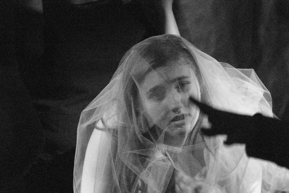 kadr ze spektaklu, czarnobiała fotografia, kobieta w sukni ślubnej spogląda przed siebie
