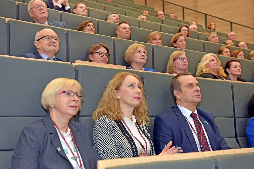 grupa ludzi siedzi w auli i słucha wystąpienia