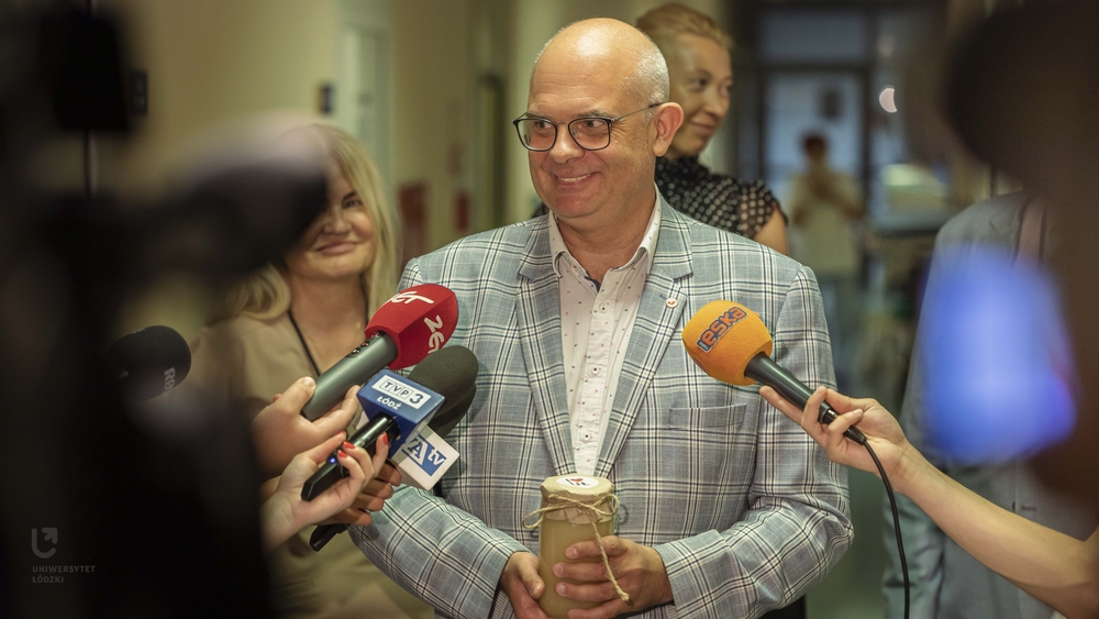 prof. Robert Zakrzewski podczas briefingu z mediami ze słoikiem miodu w dłoniach