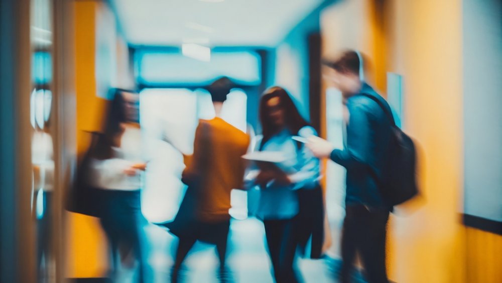 kolorowe zdjęcie przedstawiające grupę studentów rozmawiających w bibliotece uniwersyteckiej