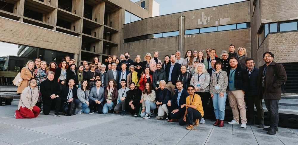 grupa pozuje na tle beżowego budynki