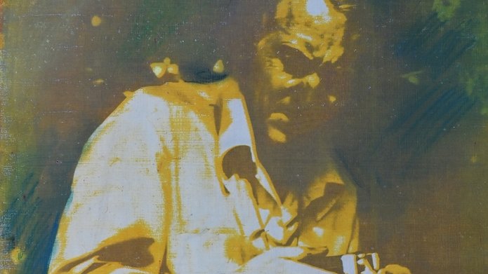 Zdjęcie przedstawia mężczyznę nachylonego nad aparatem fotograficznym.