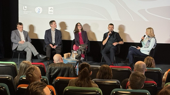 5 osób na scenie - panelistów - rozmawia w trakcie debaty 