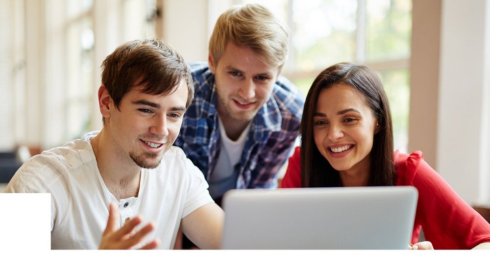 Trójka uśmiechniętych młodych ludzi, którzy siedzą przy komputerze