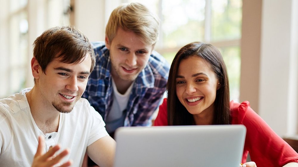 Grupa trójka młodych ludzi, którzy pracują wspólnie przy komputerze