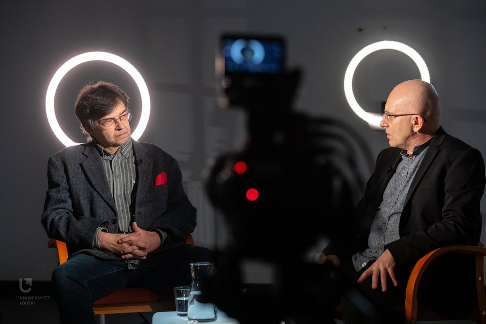 Autor tłumaczenia siedzi w sali i opowiada, gestykulując. 