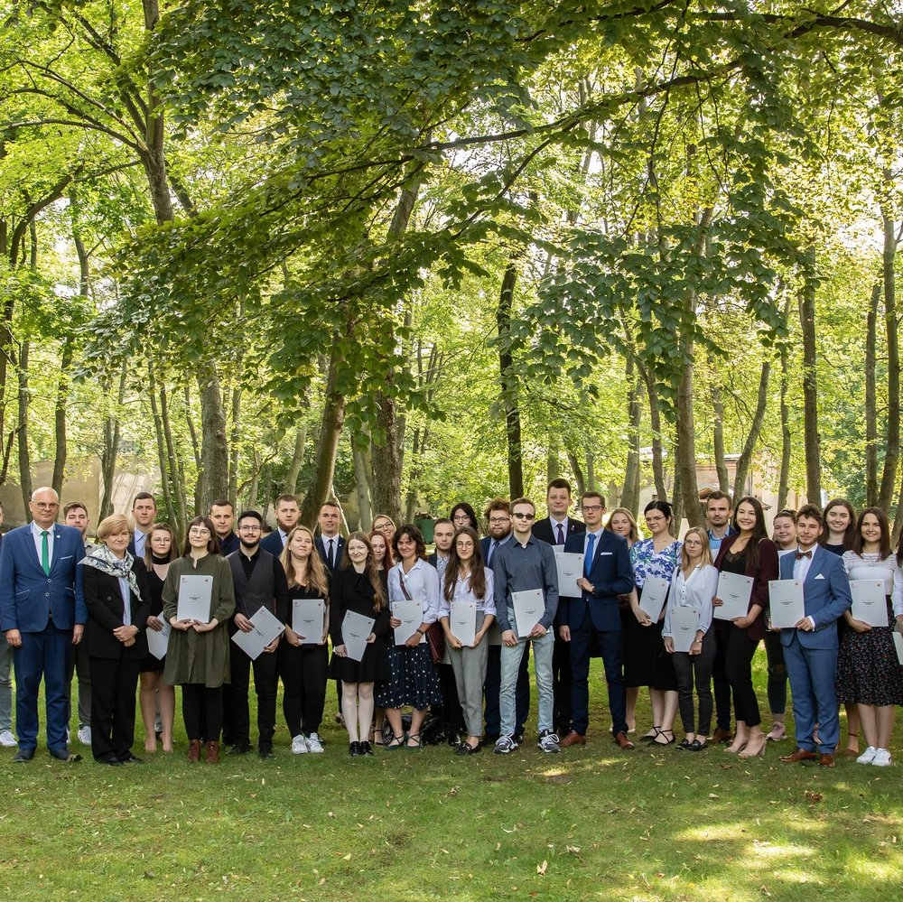 Zdjęcie grupowe wyróżnionych studentów i Władze UŁ n tle drzew 