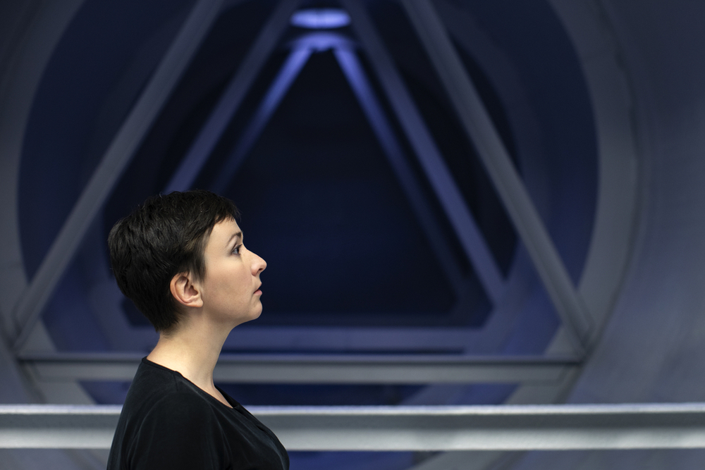 Dr Agata Zysiak z profilu. W tle metalowy element konstrukcyjny fabryki.