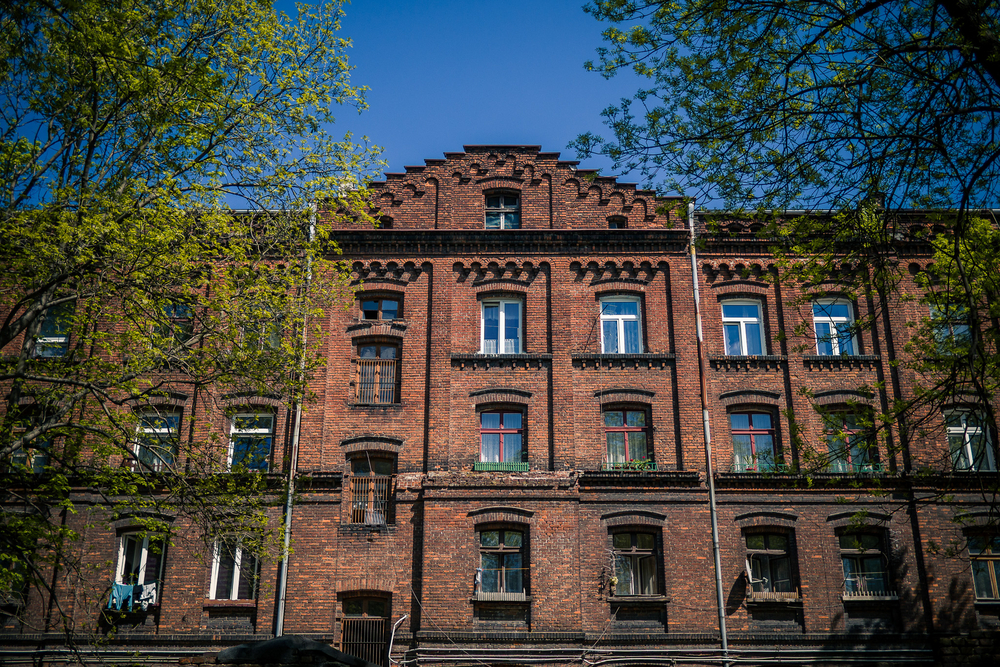 na zdjęciu widoczny jest trzykondygnacyjny budynek z cegły z poddaszem na zdjęciu widoczny jest trzykondygnacyjny budynek z cegły z poddaszem