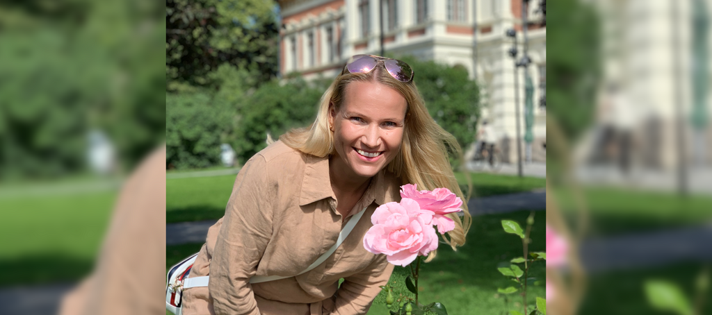 prof. Marjaana Kangas z uśmiechem pozująca przy kwiecie róży