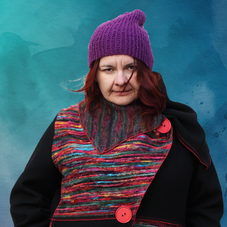 portret laureatki w płaszczu z kolorowymi akcentami w fioletowej czapce podkreślającej rudy kolor włosów