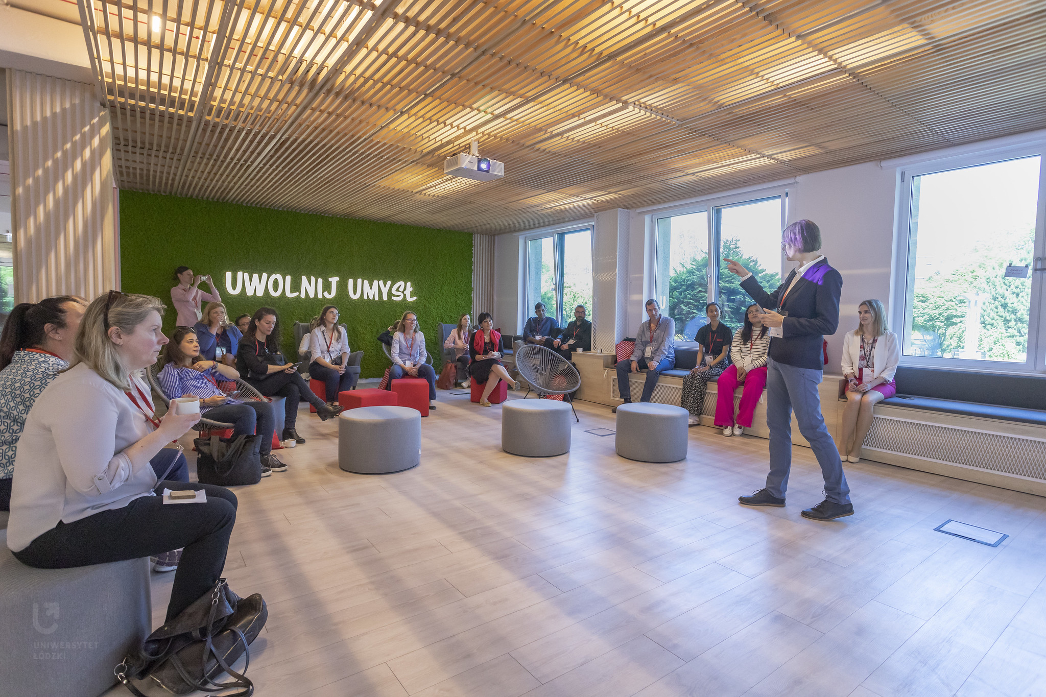 uczestnicy spotkania słuchający wykładu Liliany Lato w sali z napisem Uwolnij umysł
