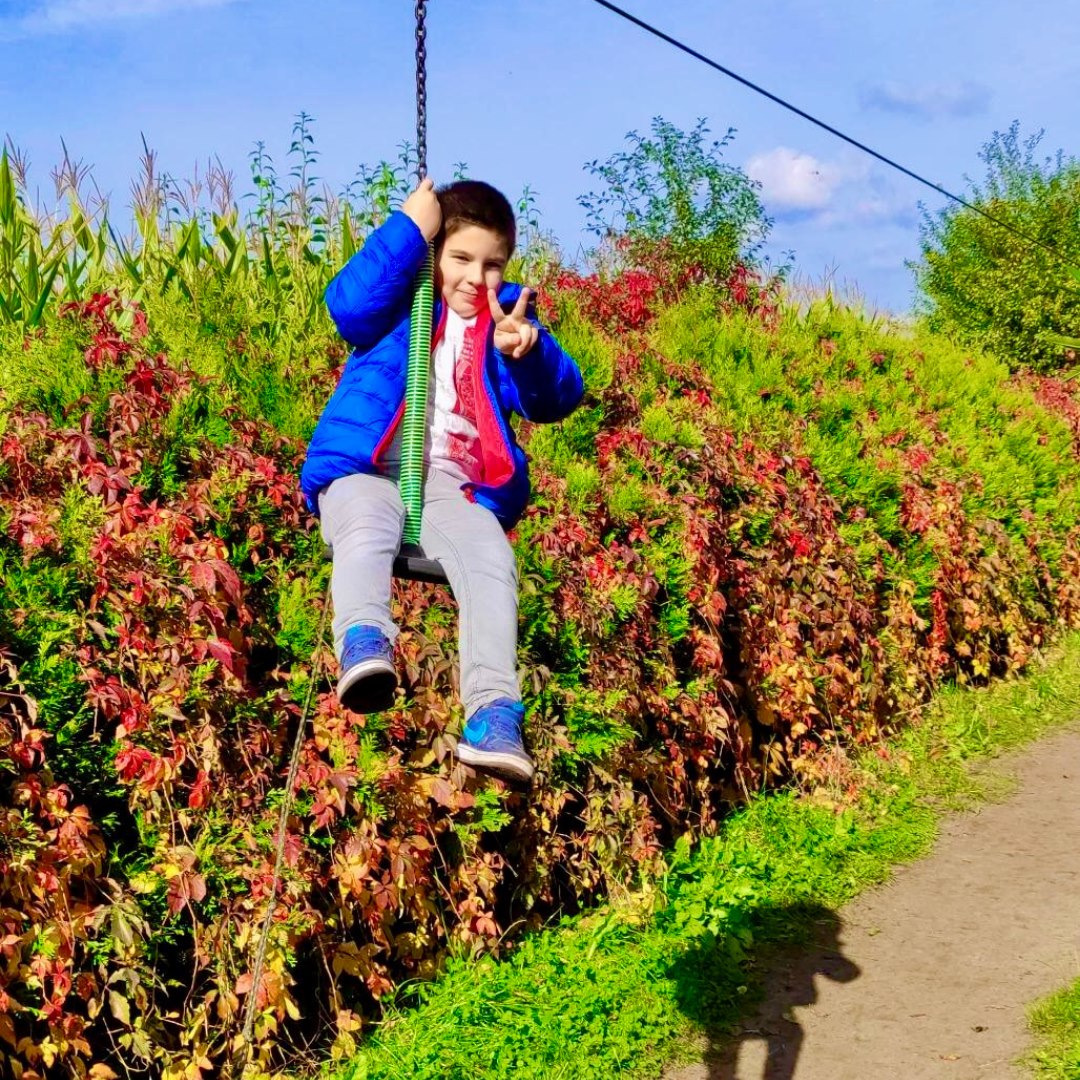 Chłopiec w niebieskiej kurtce huśtawce