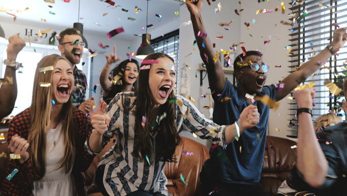 Zdjęcie przedstawiające grupę cieszących się młodych ludzi w chmurze confetti.