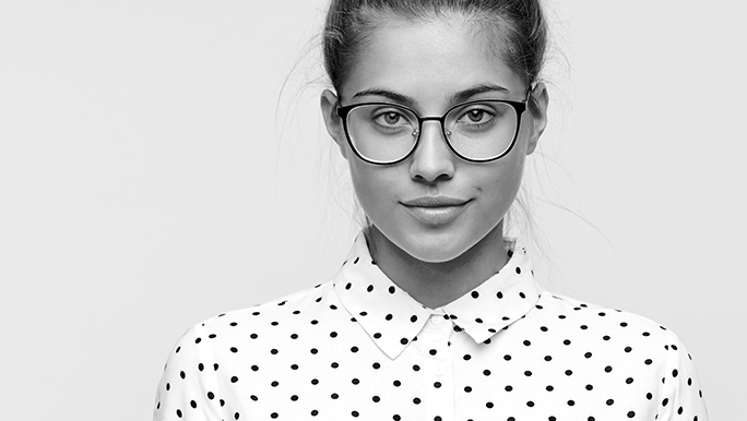 Czarno-białe zdjęcie pokazujące młodą uśmiechniętą studentkę, zdjęcie ilustruje artykuł poświęcony rozpoczęciu kolejnej edycji Studenckich Grantów Badawczych Uniwersytetu Łódzkiego