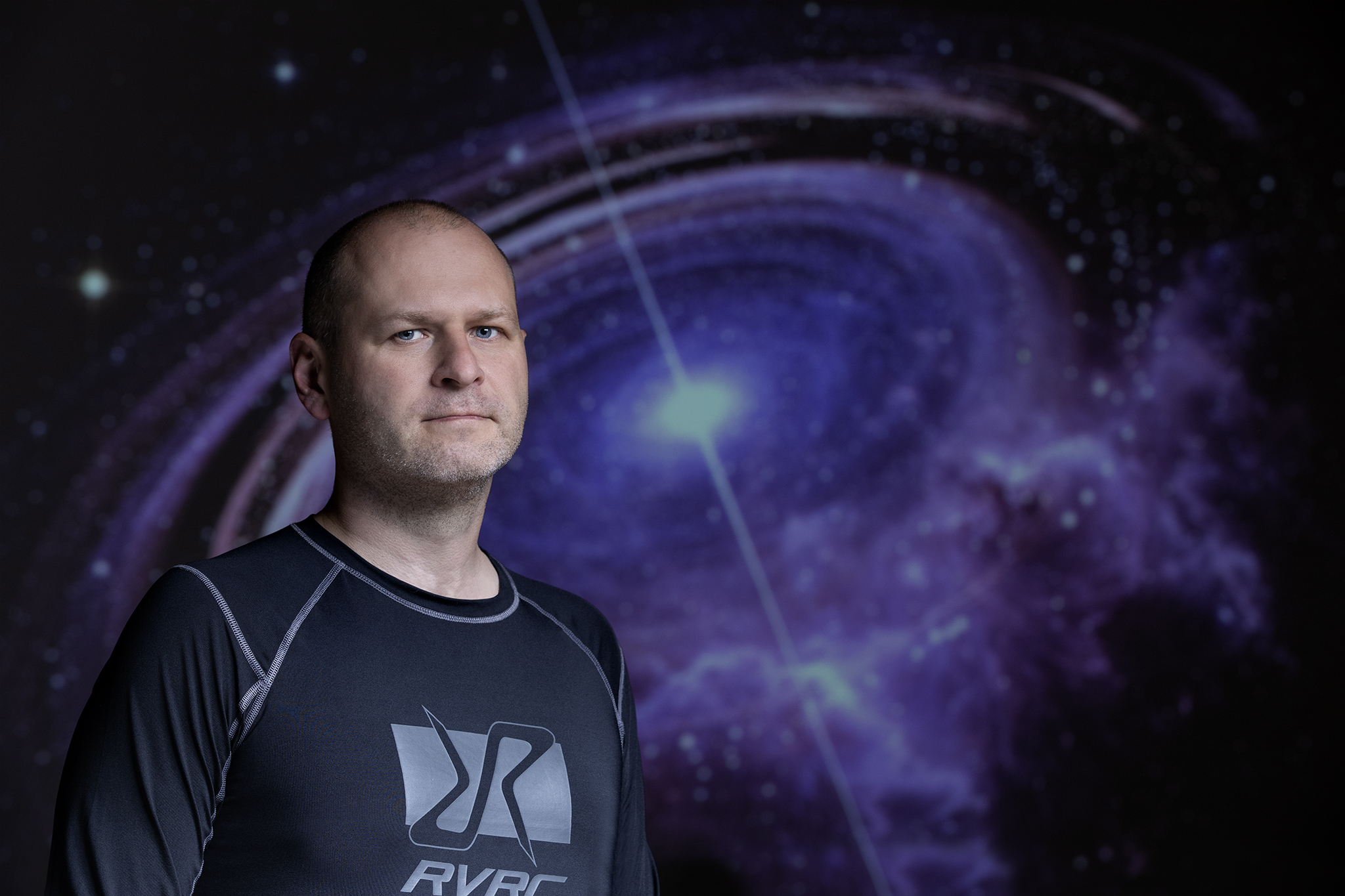 dr Michał Szanecki na tle zdjęcia z gwiazdą neutronową