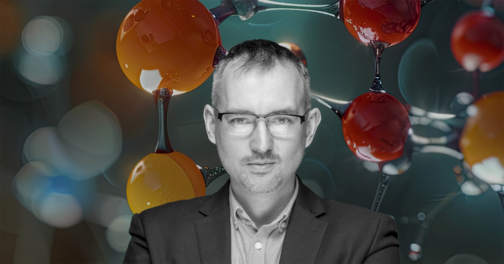 Zdjęcie portretowe dra hab. Łukasza Półtoraka, prof. UŁ na tle kulek symbolizujących molekuły