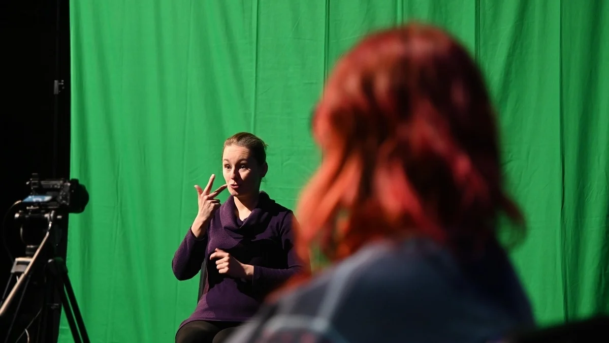 Zdjęcie przedstawia osobę migającą i osobę patrzącą w stronę migaczki