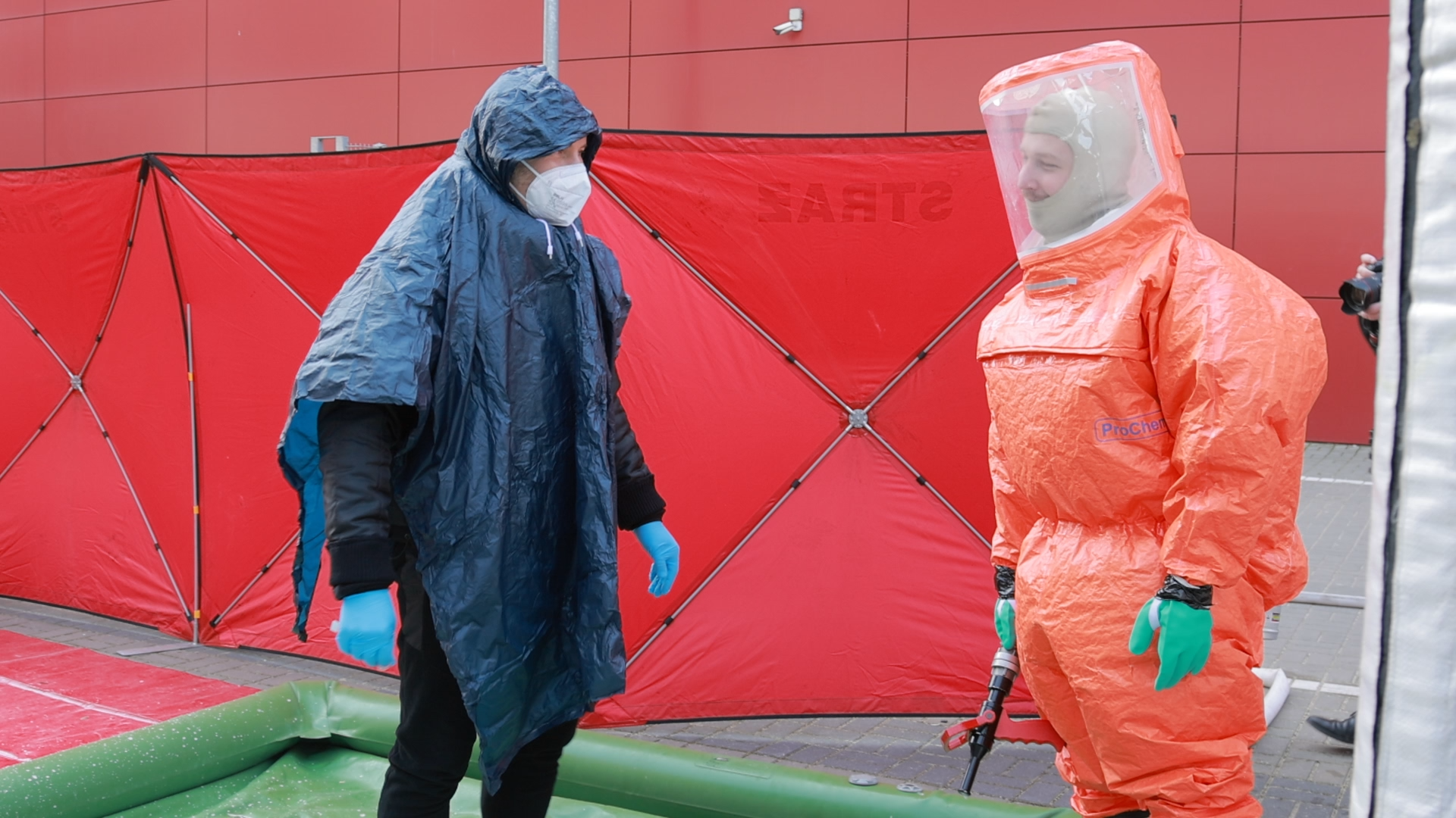 dwie osoby w strojach zabezpieczających ciało przed skażeniami 