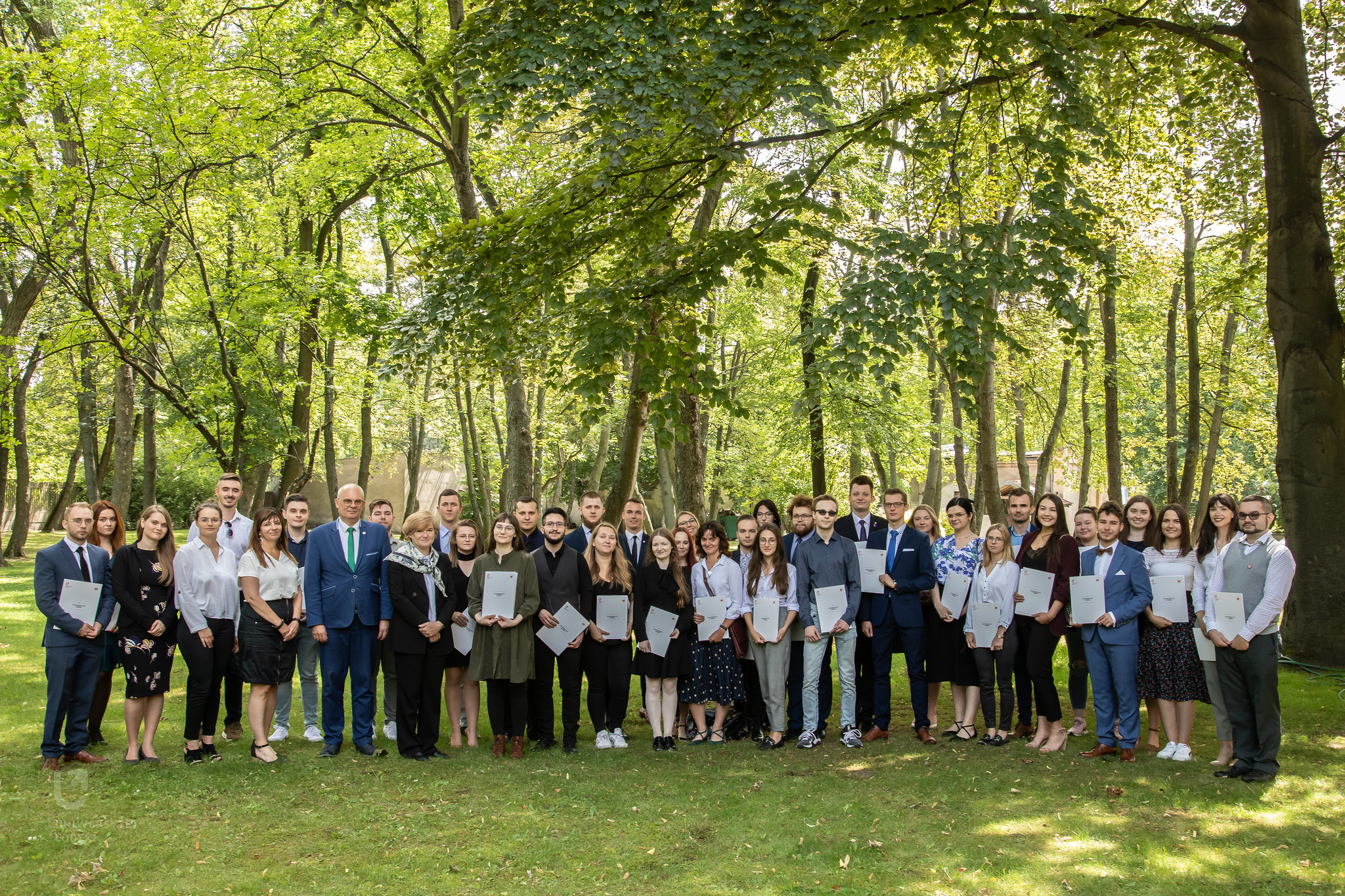 Zdjęcie grupowe wyróżnionych studentów i Władze UŁ n tle drzew 