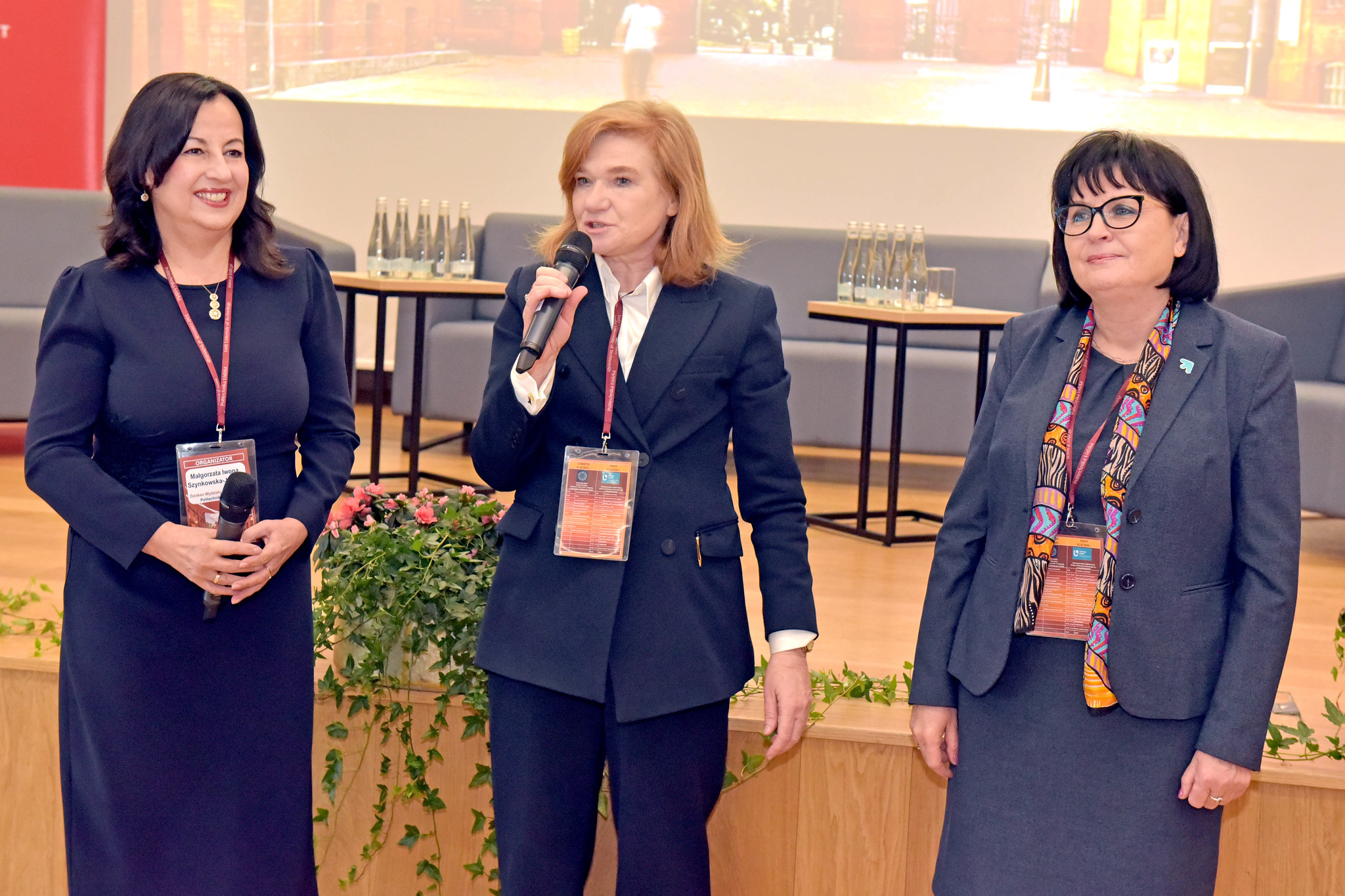 trzy kobiety stoją w auli i przemawiają 